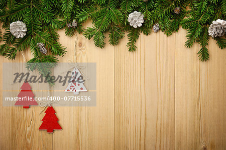 Christmas background with fresh firtree, decorative handmade trees and cones on wood