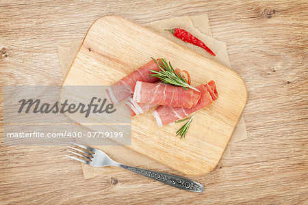 Prosciutto with spices. Over wooden table background