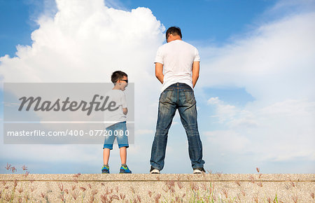 father and son standing on a stone platform and pee together