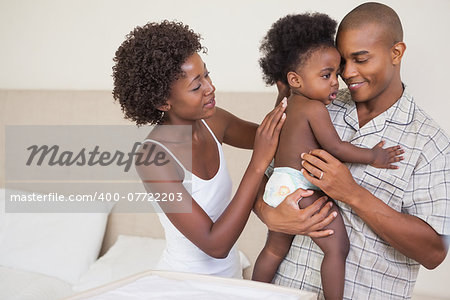Happy parents with their baby girl at home in the bedroom