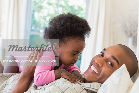 Happy father and baby girl lying on bed together at home in the bedroom