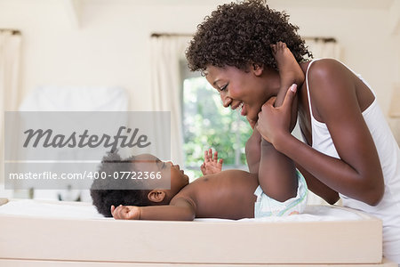 Happy mother with baby girl on changing table at home in the bedroom