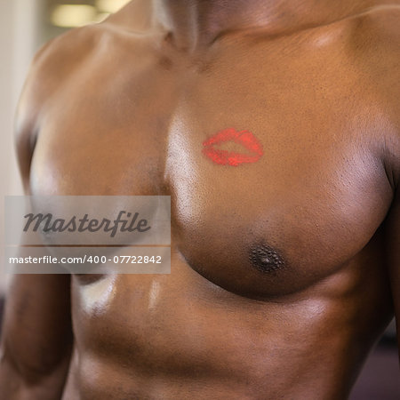 Close-up mid section of a shirtless muscular man with lipstick mark on chest