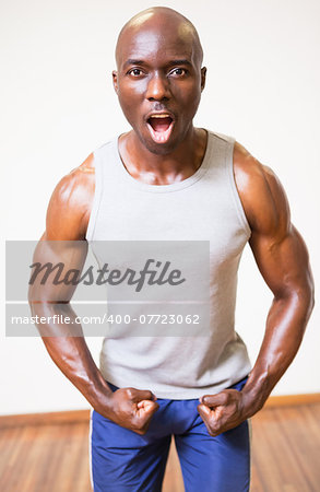 Portrait of a muscular man shouting while flexing muscles in gym