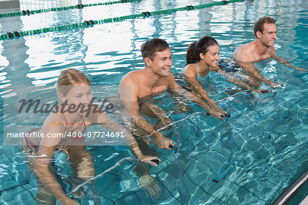 Fitness class doing aqua aerobics on exercise bikes in swimming pool at the leisure centre