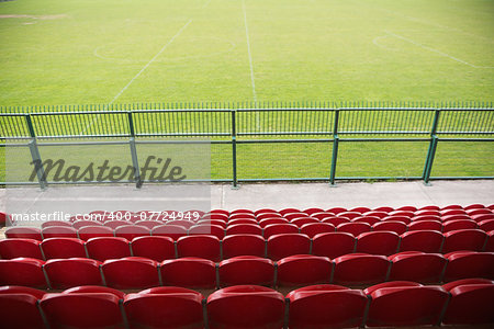 Red bleachers looking down on football pitch on a clear day