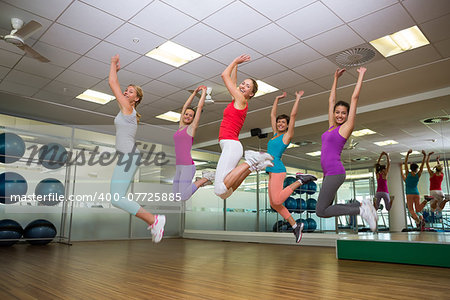 Fitness class jumping up in studio at the gym