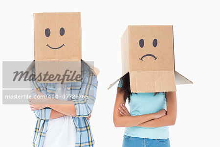 Young couple wearing sad face boxes over head on white background