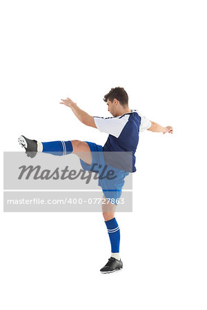 Football player in blue jersey kicking on white background