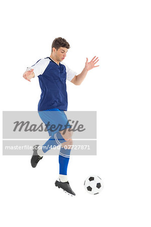 Football player in blue jersey kicking ball on white background