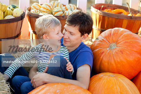 happy young father and his cute son spending fun time together at pumpkin patch; family of two at fall