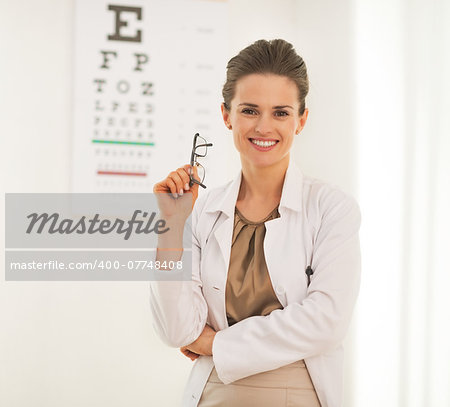 Portrait of doctor woman with eyeglasses in front of snellen chart