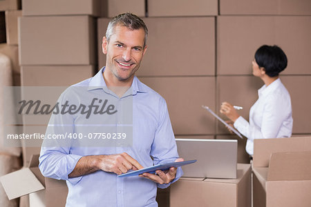 Warehouse manager using his tablet pc in a large warehouse