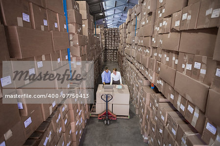Warehouse team working together with trolley in a large warehouse