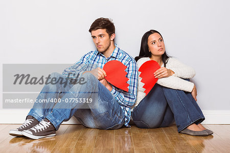 Young couple sitting on floor with broken heart at home