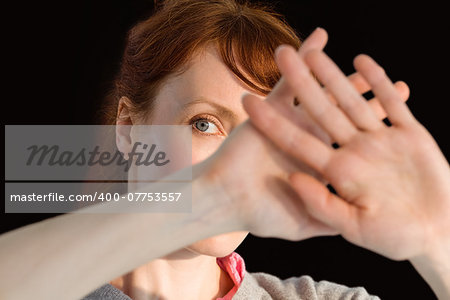 Scared woman covering her face on black background