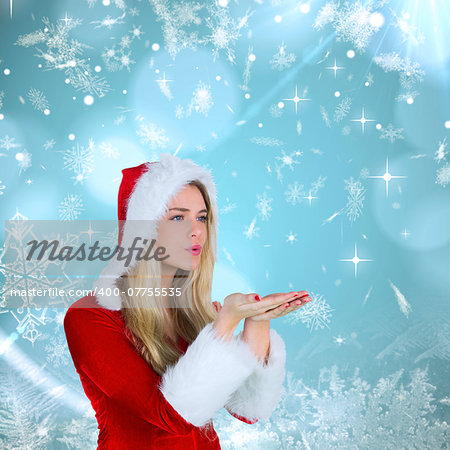Pretty girl in santa outfit blowing against blue snow flake pattern design