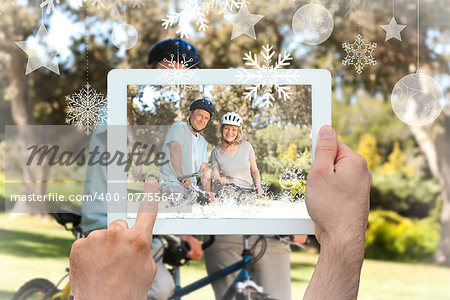 Hands holding tablet pc against elderly couple with their bikes