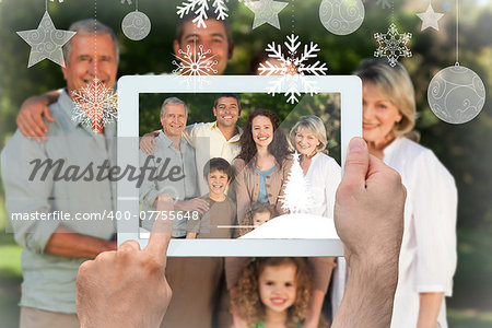 Hands holding tablet pc against family looking at the camera in the park