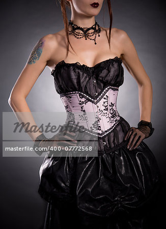 Elegant woman in corset with floral pattern, studio shot on black background