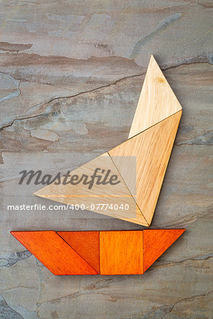 abstract picture of a sailing yacht built from seven tangram wooden pieces over a slate rock background, artwork created by the photographer