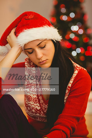 Festive brunette feeling sad at christmas at home in the living room