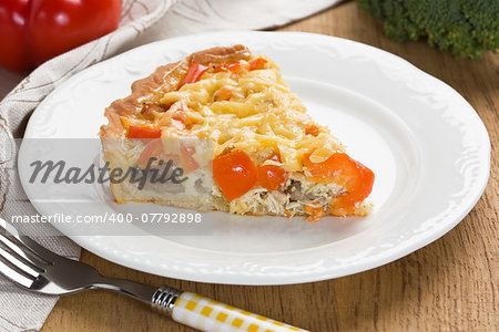 Quiche pie with chicken, red pepper, ham and mushroom on white plate