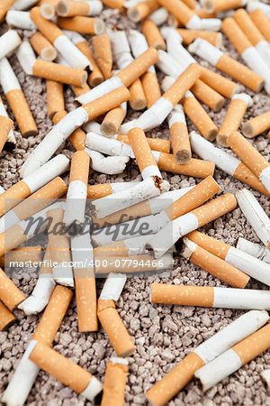 Ashtray full of smoked fallen cigarettes in the sand