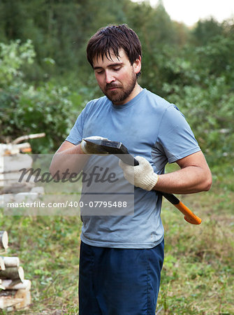 Young lumberman in a forest with an axe in his hands