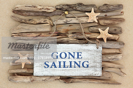 Starfish and gone sailing old weathered sign on driftwood and beach sand background.