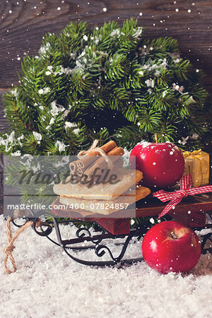 Christmas decoration with decorative sled and sweet cookies with red winter apples. Toned photo.
