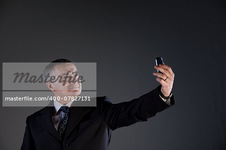 A senior manager using successfully his inseparable smartphone agenda and calendar, now taking a selfie
