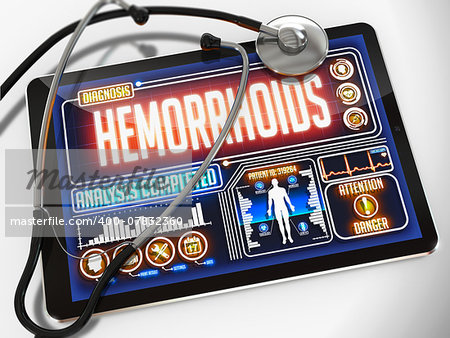 Medical Tablet with the Diagnosis of Hemorrhoids on the Display and a Black Stethoscope on White Background.