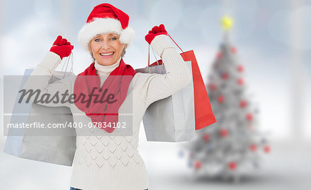 Festive woman holding shopping bags against blurry christmas tree in room