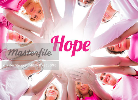Diverse women smiling in circle wearing pink for breast cancer on white background