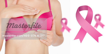 Woman performing self breast examination against pink breast cancer awareness ribbons