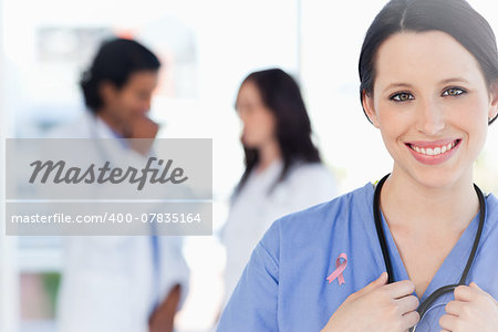 Confident nurse standing wearing breast cancer awareness ribbon