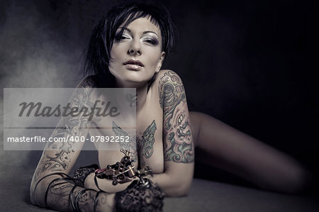 Beautiful woman with many tattoos posing indoors