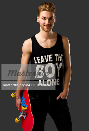 Studio portrait of a young man posing with a skateboard