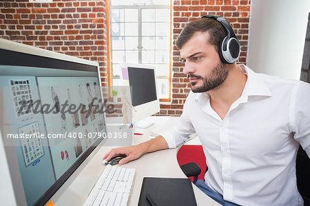 Side view of concentrated male photo editor using computer in the office