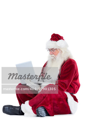 Santa sits and uses a laptop on white background