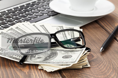 Office table with pc, coffee cup and glasses over money cash closeup
