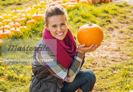 Portrait of happy young woman showing pumpkin