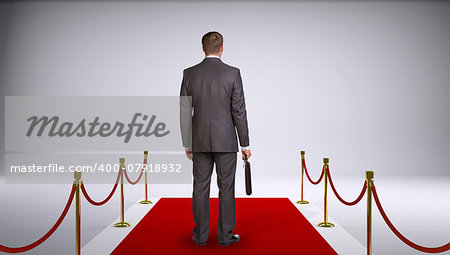 Businessman in suit holding briefcase and standing on red carpet. Rear view. Business concept