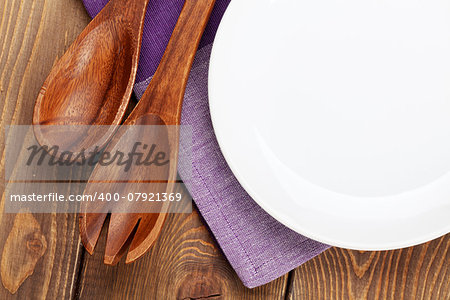 Wood kitchen utensils and empty plate over wooden table background with copy space