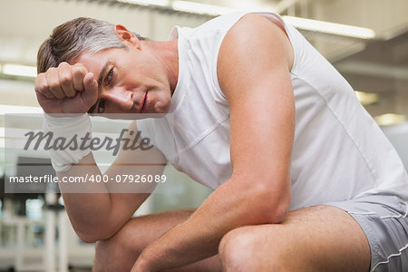 Fit man taking a break in the weights room at the gym