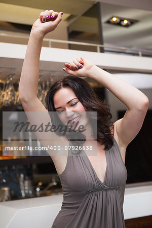 Pretty brunette dancing with hands up at the nightclub