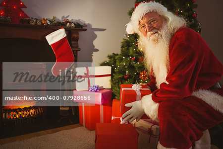 Smiling santa delivering gifts at christmas eve at home in the living room