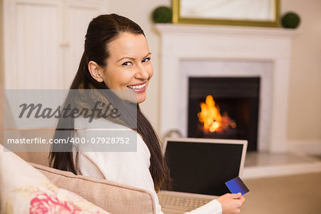 Woman doing online shopping with laptop and credit card at home in the living room