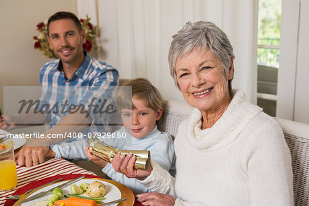 Smiling family pulling christmas crackers at the dinner table at home in the living room